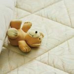 Ours en peluche heureux sur un matelas / Blog Peliqan